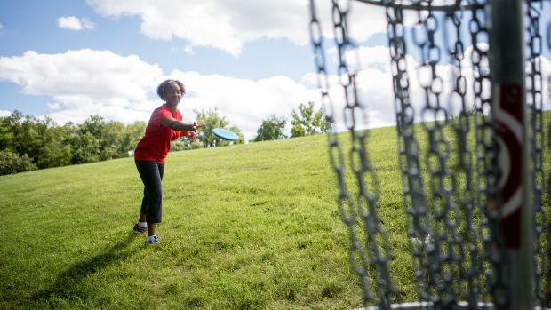 Student throwing a disc toward a basket on Logan University's campus course