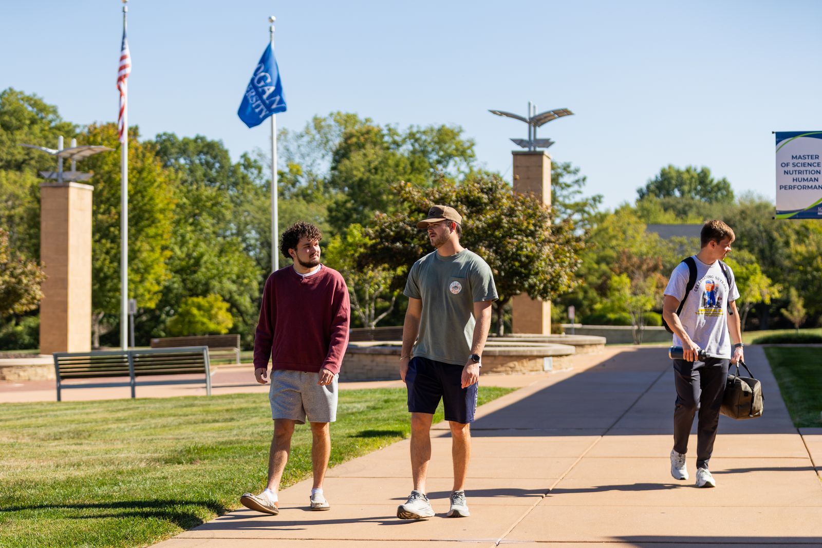 Students walk past the flagpoles on Logan University's campus