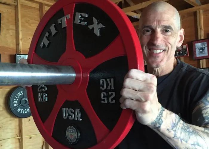 Kenneth Evan Leistner, DC, holding an Olympic barbell loaded with a 25 kg plate